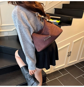 Detail of dark brown suede tote with stylish beaded strap and silver fashion plaque