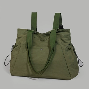 Detail of army green waterproof nylon tote bag featuring side drawstrings and metal snap