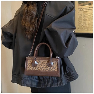 Detail of a vintage leopard print handbag with glossy leather finish and silver hardware