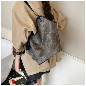 Detail of a large smoky gray hobo shoulder bag showing its texture and black leather trim