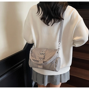 Détail du sac à bandoulière gris avec boucles métalliques et pochette ronde zippée latérale