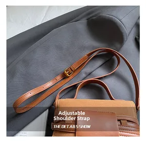 Close-up of adjustable strap on brown suede handbag with elegant gold metal buckle