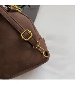 Detail of dark brown matte suede fabric and shiny golden metal hardware on backpack