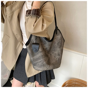 Detail of vintage grey tote bag with washed texture and black shoulder strap shown on model
