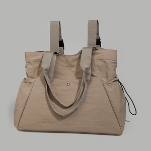 Detail of khaki nylon tote bag showing durable fabric, buckle straps, and front metal fastener