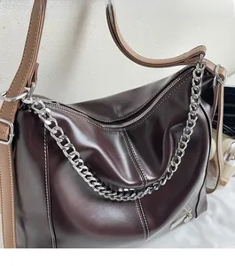 Détail du sac cabas en cuir marron avec surpiqûres blanches et chaîne argentée décorative