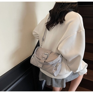 Détail du sac bandoulière en nylon gris argenté avec texture mate et rabat à œillets