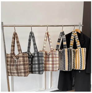 Detail view of five checkered and striped plush tote bags hanging on a metal rack