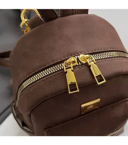 Close-up of brown frosted faux leather mini bag featuring smooth golden dual metal zippers