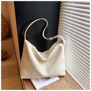 Detail of a creamy white large tote bag with textured lychee grain leather on a windowsill