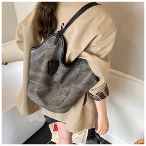 Detail of a large vintage-style tote bag with washed texture and black leather straps