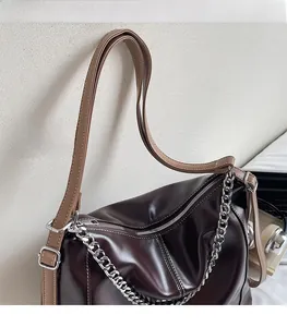 Détail de la texture en similicuir marron foncé et bandoulière réglable avec chaîne en métal