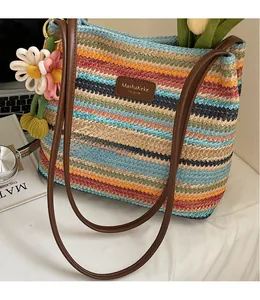 Detail der bunt gestreiften gewebten Beuteltasche mit braunem Lederriemen und Blumenanhänger