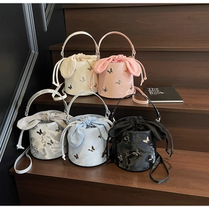 Detailed close-up of mini bucket bags with drawstring and metal butterfly accents in five colors