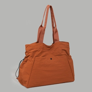 Detail of water-resistant caramel tote bag showing reinforced handles and side drawstring pocket