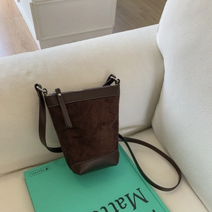 Detail of dark brown matte leather bucket bag texture and smooth leather strap