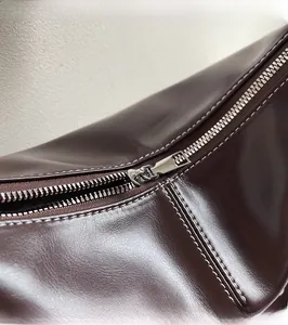 Vue détaillée de la fermeture éclair en métal argenté sur le sac en cuir marron
