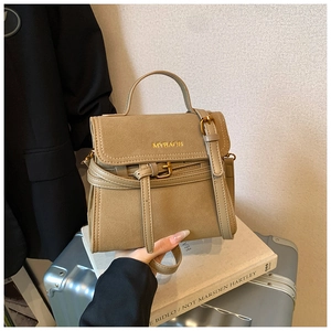 Detail showing the retro khaki suede texture and golden brand logo on the handbag