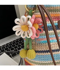 Nahaufnahme von handgewebtem Blumenanhänger mit Gänseblümchen und Goldverschluss
