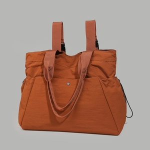 Detailed view of the brick red water-resistant nylon tote backpack showing convertible straps