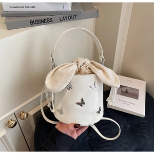 Detail of white bucket bag with silver butterfly rivets and bunny ear drawstring closure