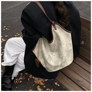 Close-up of marble pattern tote bag with brown trim on model seated on a bench