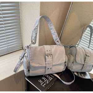 Détail du sac bandoulière argenté avec œillets métalliques et poche latérale zippée