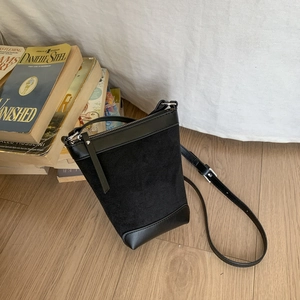 Detail view of black leather bucket bag with silver zipper resting on books