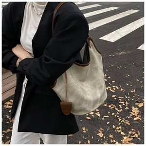 Detailed view of grey vintage tote bag with brown leather trim in a street style setting