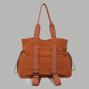 Front view of water-resistant orange tote bag with side drawstrings and nylon texture