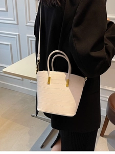 White croc-effect bucket bag with gold hardware worn by model in black blazer