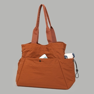 Detail view of rust orange waterproof nylon tote bag with functional pockets and large capacity
