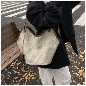 Outdoor shot of a grey marble-textured tote bag with brown leather straps and autumn vibes
