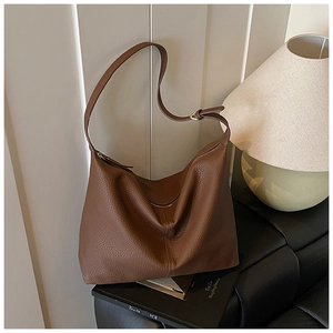 Close-up of vintage brown pebble leather tote bag with metallic zipper and adjustable strap