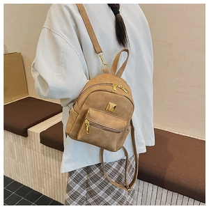 Detail of a brown suede mini backpack featuring gold zipper hardware and front metal accents