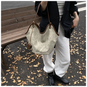Detail of vintage beige bucket bag with dark brown leather trim on autumn street
