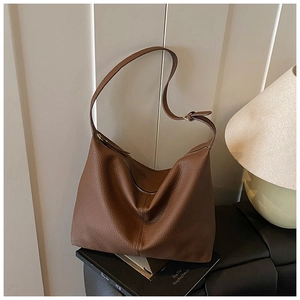 Detail of a brown pebble grain leather hobo bag with adjustable strap on a bench