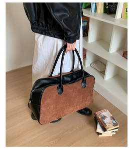 Detail of a large brown suede and black leather patchwork tote bag in a lifestyle setting