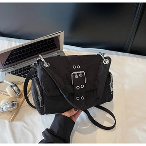 Vue détaillée du sac bandoulière en toile noire avec boucles argentées et zips latéraux