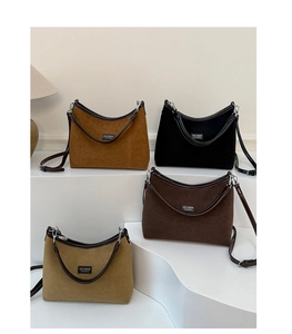 Detail view of suede matte handbags in four colors displayed on minimalist steps