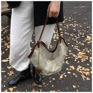 Detail view of large grey-green leather tote bag with brown contrast trim and strap