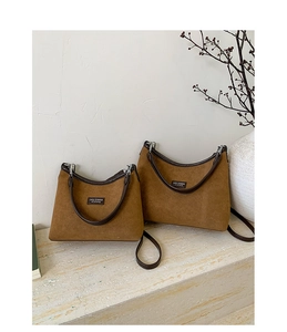 Detail of small and large brown suede handbags with Lazy Breeze logo and silver buckles