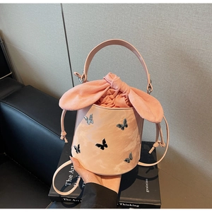 Detailed view of pink bucket bag featuring 3D silver butterflies and a bow drawstring