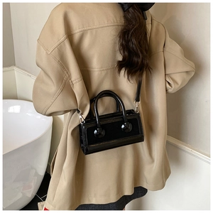 Model wearing a vintage black crossbody bag with glossy finish and silver hardware