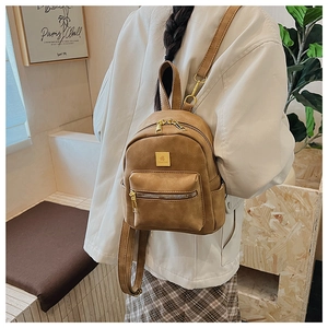 Rear view of a model wearing the brown vintage faux leather mini backpack in a cozy room