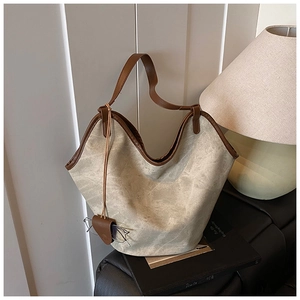 Detail of oatmeal canvas bucket bag featuring dark brown leather trim and glasses accessory