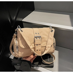 Détail du sac à bandoulière en toile kaki avec grande boucle argentée et poches zippées