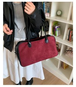 Detail view of burgundy suede tote bag with black leather edges and dual handles