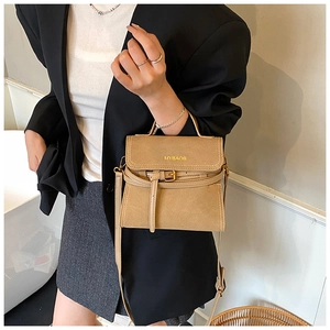 Detail of camel frosted leather handbag featuring golden metal hardware and top handle