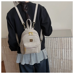 Detailed view of mini faux leather backpack with gold-tone hardware and logo plaque